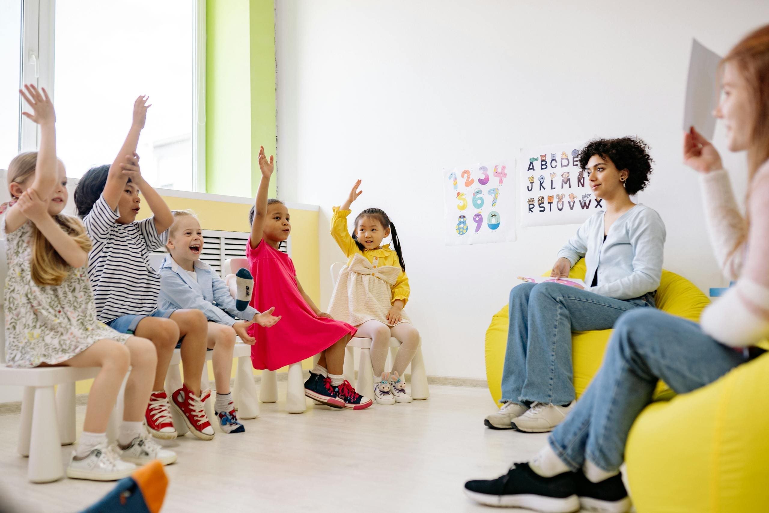 Children actively participate in a classroom with teachers, showcasing diversity and engagement.