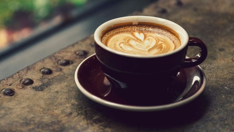 A beautifully crafted cup of latte with heart-shaped art on a rustic table.