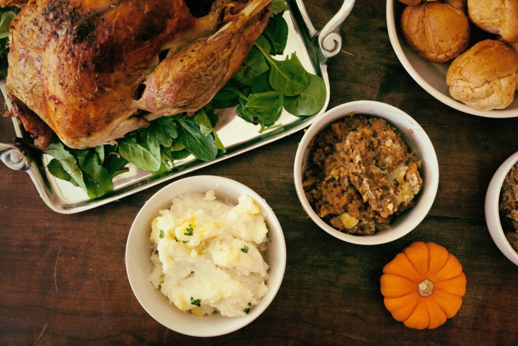 thanksgiving table with turkey, mashed potatoes, rolls, and stuffing