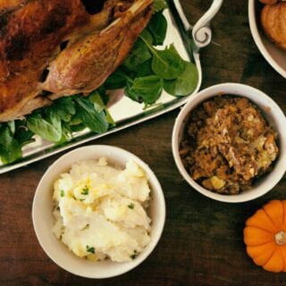thanksgiving table with turkey, mashed potatoes, rolls, and stuffing