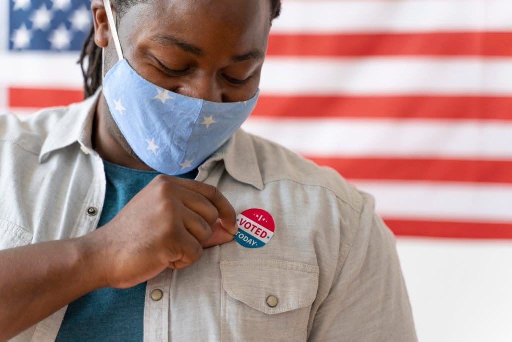 African American man wearing a mask with an I Voted sticker