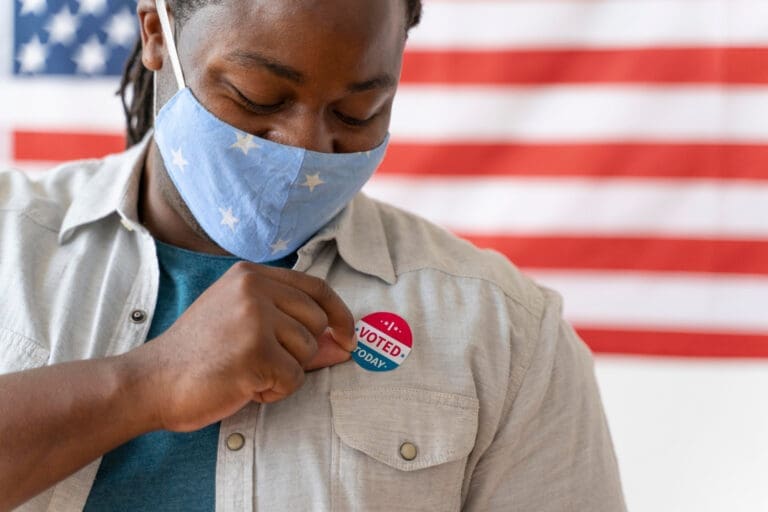 African American man wearing a mask with an I Voted sticker