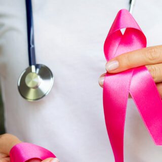 A healthcare provider holding a pink breast cancer ribbon.