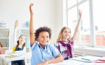 School-aged children raise their hands in a classroom setting. In 2000, measles was declared eliminated in the US — so why are some states, including nearby Kansas, having measles outbreaks now? The answer isn’t a mystery: fewer kids are getting vaccinated against measles.