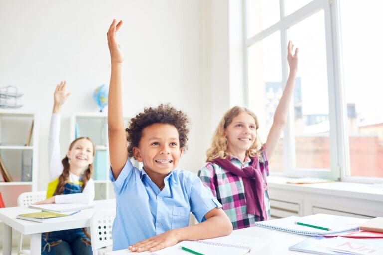 School-aged children raise their hands in a classroom setting. In 2000, measles was declared eliminated in the US — so why are some states, including nearby Kansas, having measles outbreaks now? The answer isn’t a mystery: fewer kids are getting vaccinated against measles.