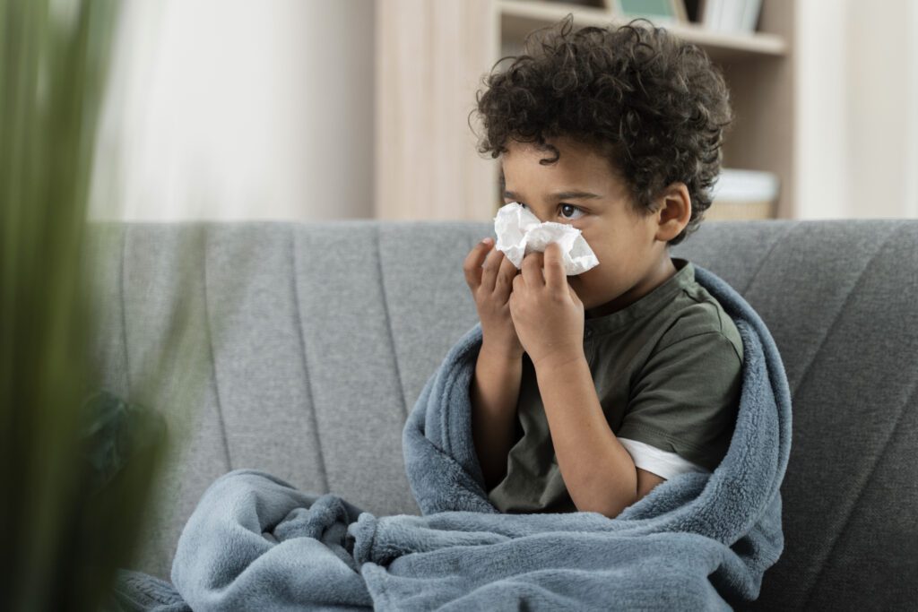 Image of a sick boy blowing his nose.
