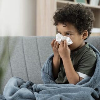 Image of a sick boy blowing his nose.