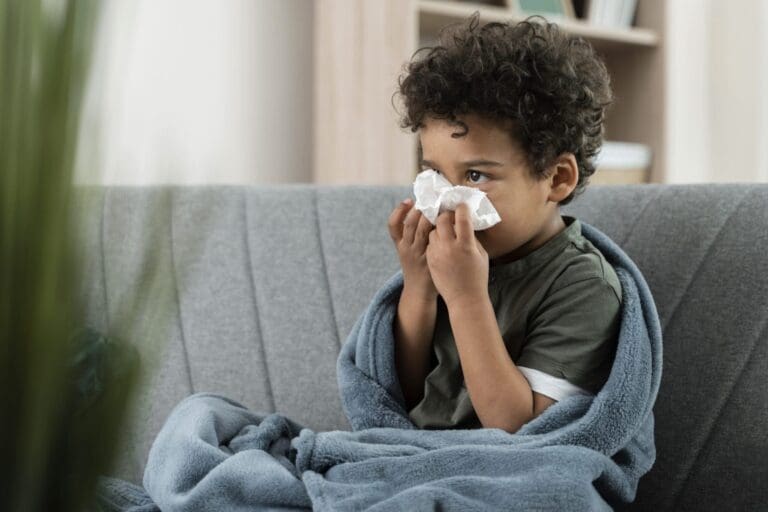 Image of a sick boy blowing his nose.