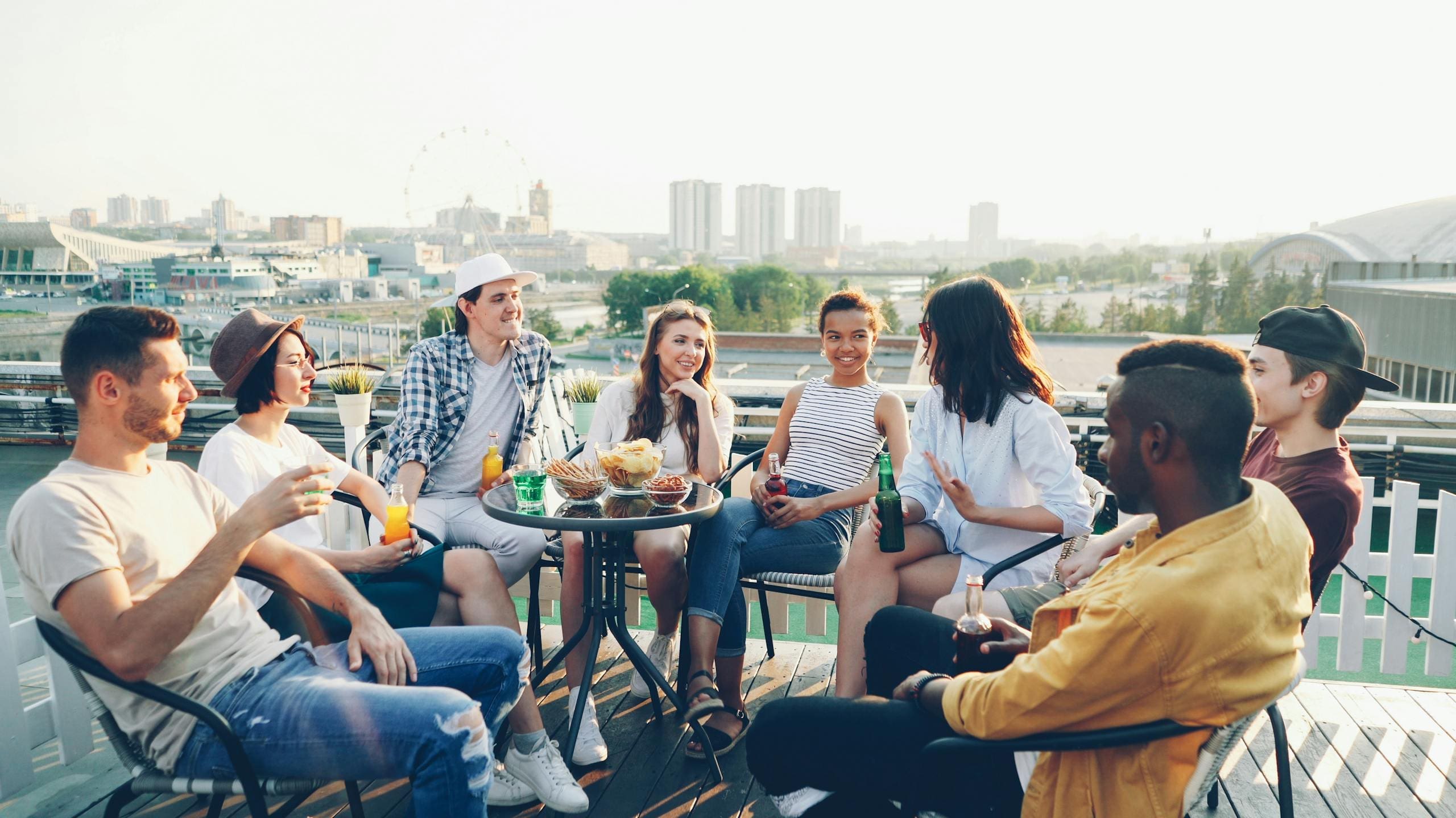 Friends enjoying a summer rooftop party with drinks and snacks.